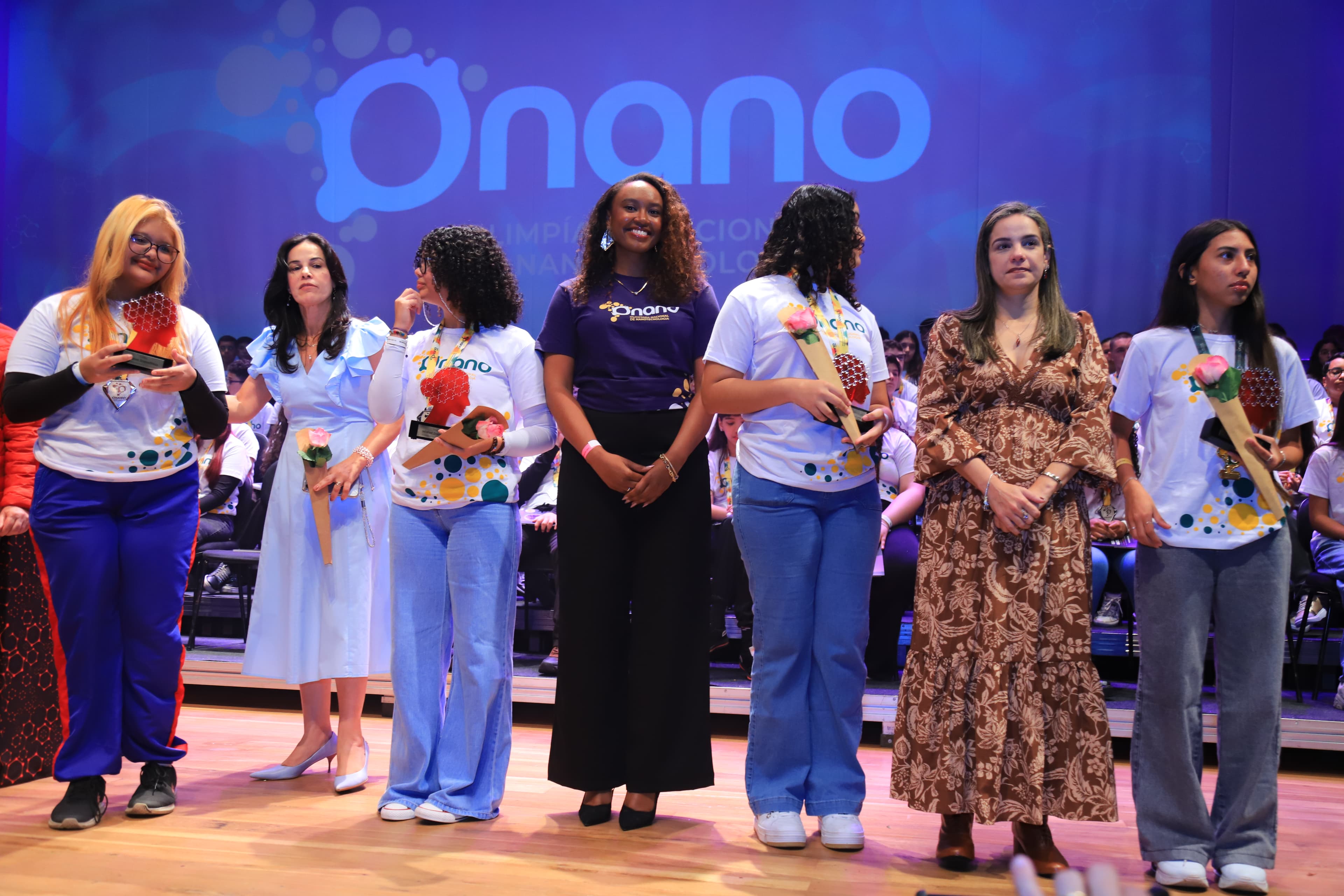 Grupo de medalhistas e organizadoras no palco da premiação da ONANO